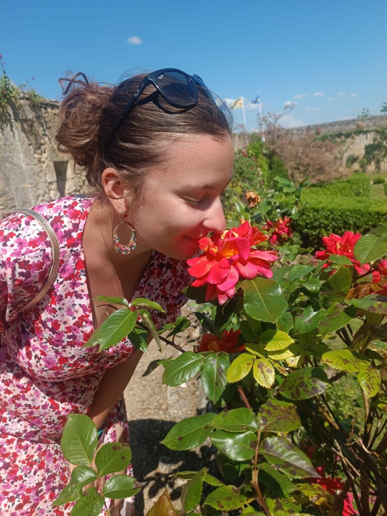 Personne sentant une fleur dans les jardins fleuris du château de Montreuil-Bellay.